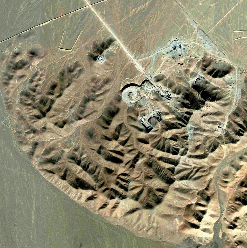 an aerial view of a desert landscape with mountains and a road