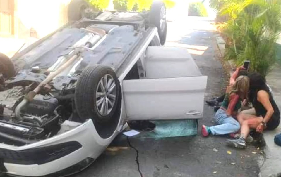 Car crash victims pose for a selfie next to their wrecked vehicle