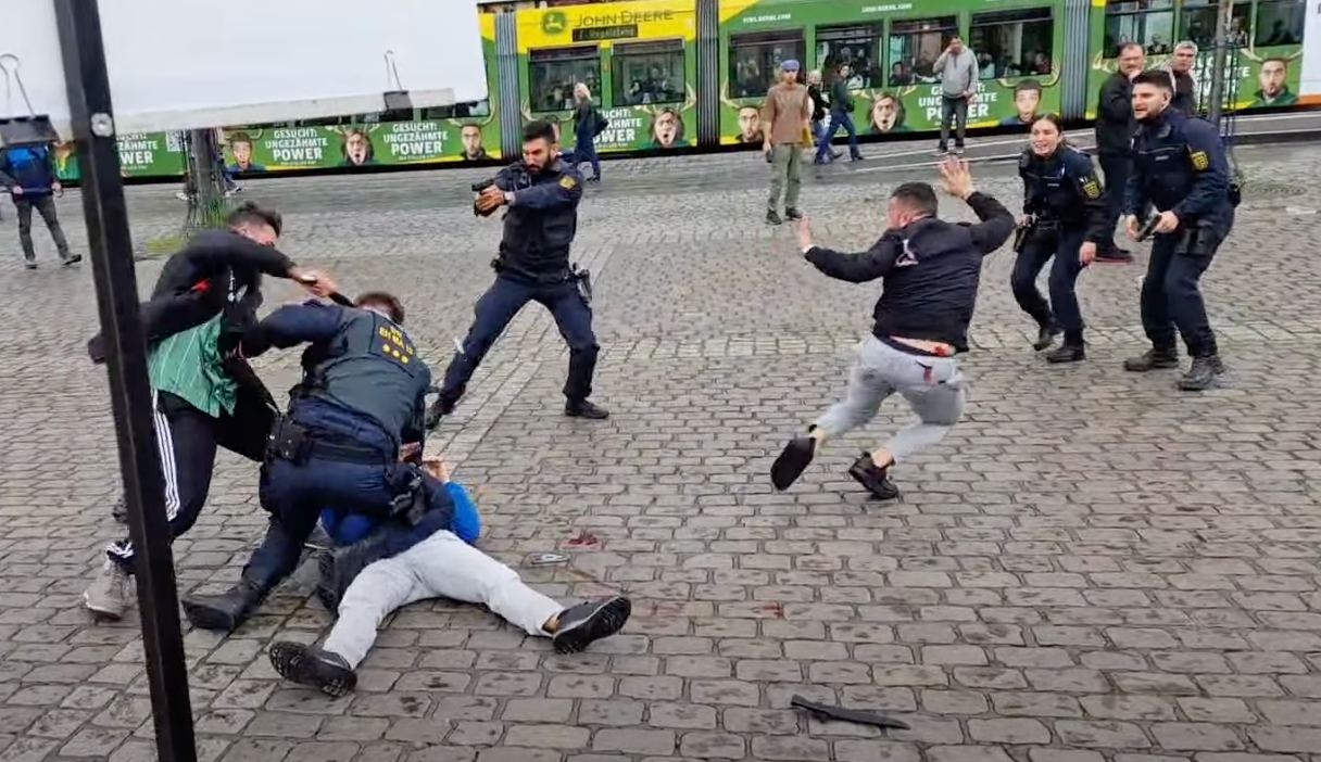 The attacker appears to stab a police officer in the back and side