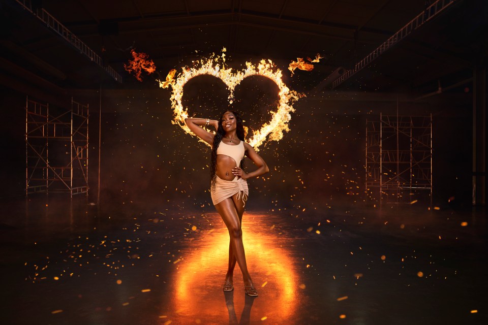 a woman stands in front of a heart made of flames