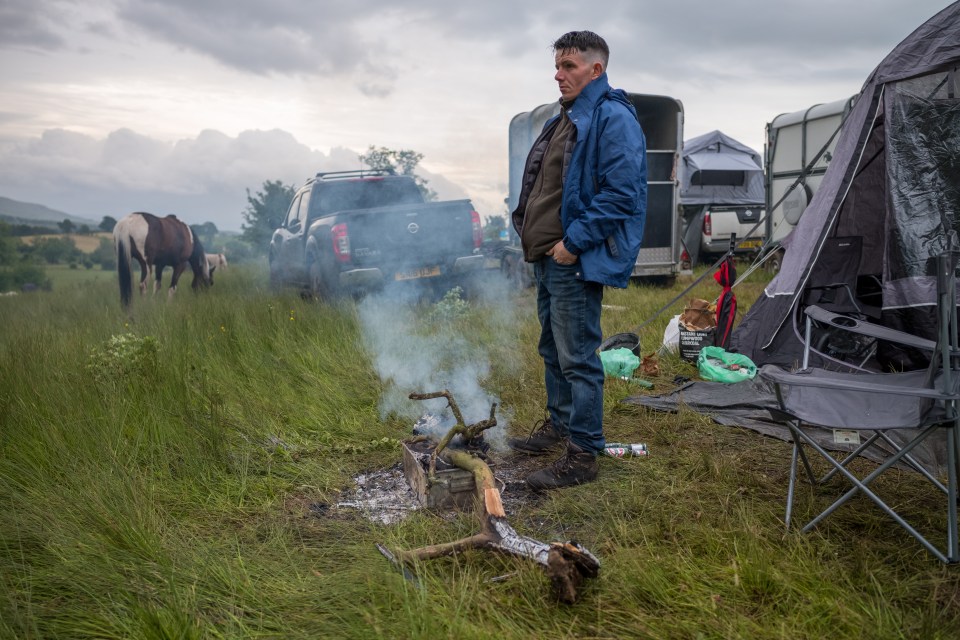 A man stands next to his fire in the early morning at Appleby Horse Fair on Saturday