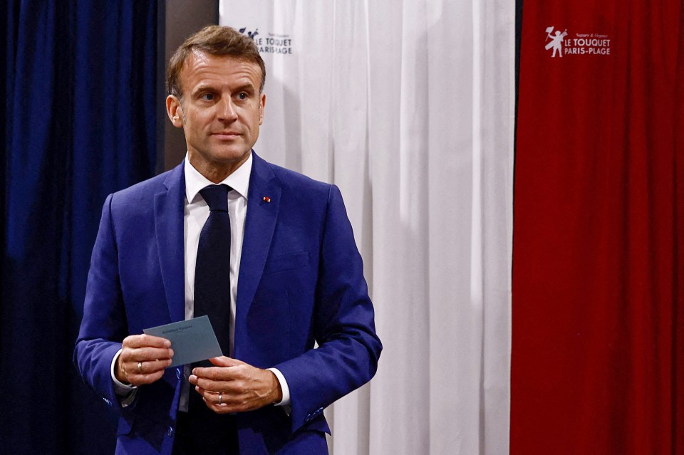 a man in a blue suit and tie stands in front of a curtain that says le touquet paris-plage