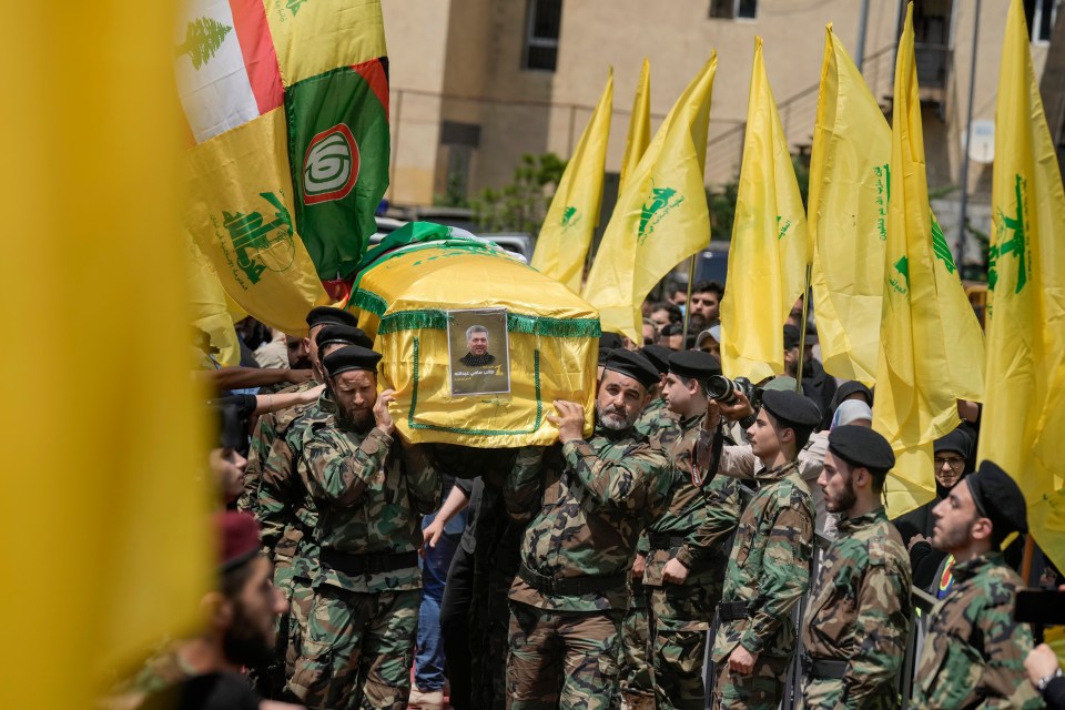 soldiers carry a coffin with a picture of a man on it