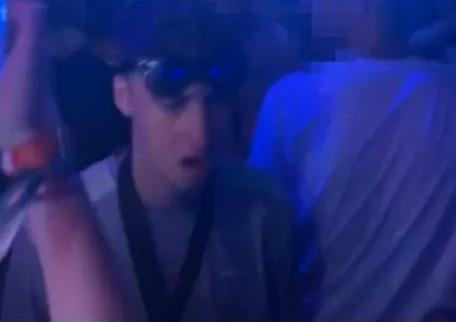 a man wearing sunglasses is standing in a crowd of people at a party .