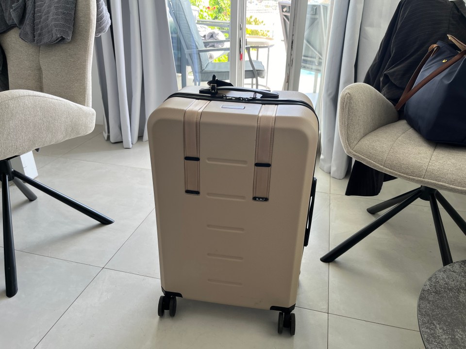 Beige suitcase on a tiled floor.