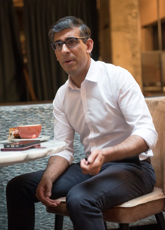 a man wearing glasses sits at a table with a cup of coffee