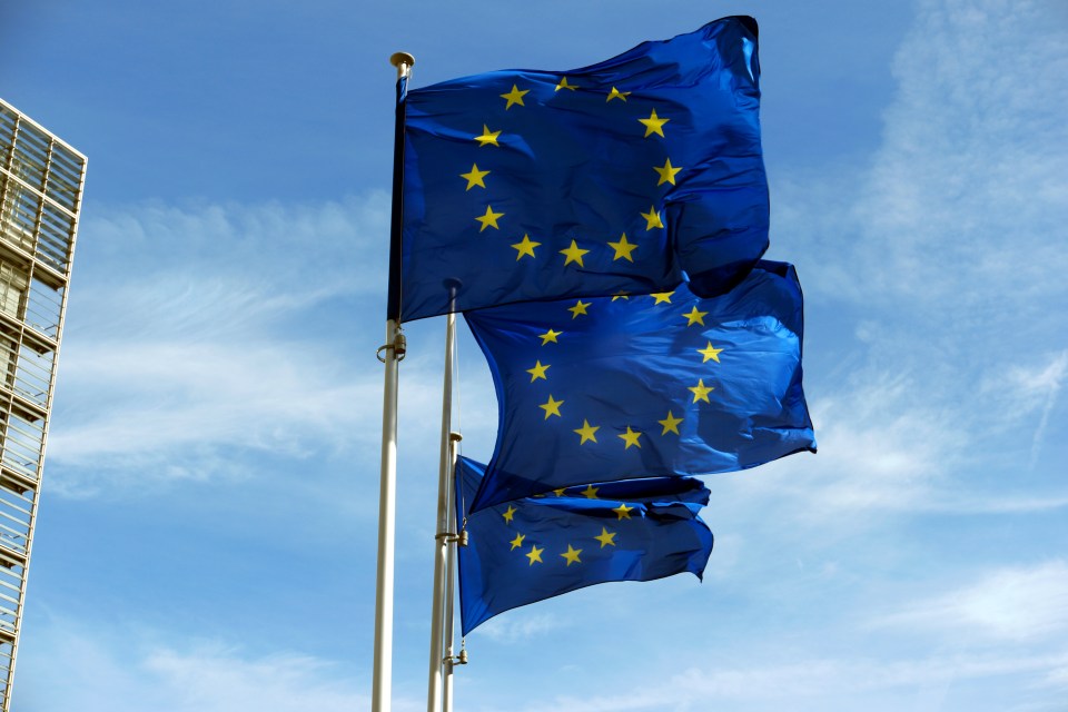 three blue flags with yellow stars are waving in the wind