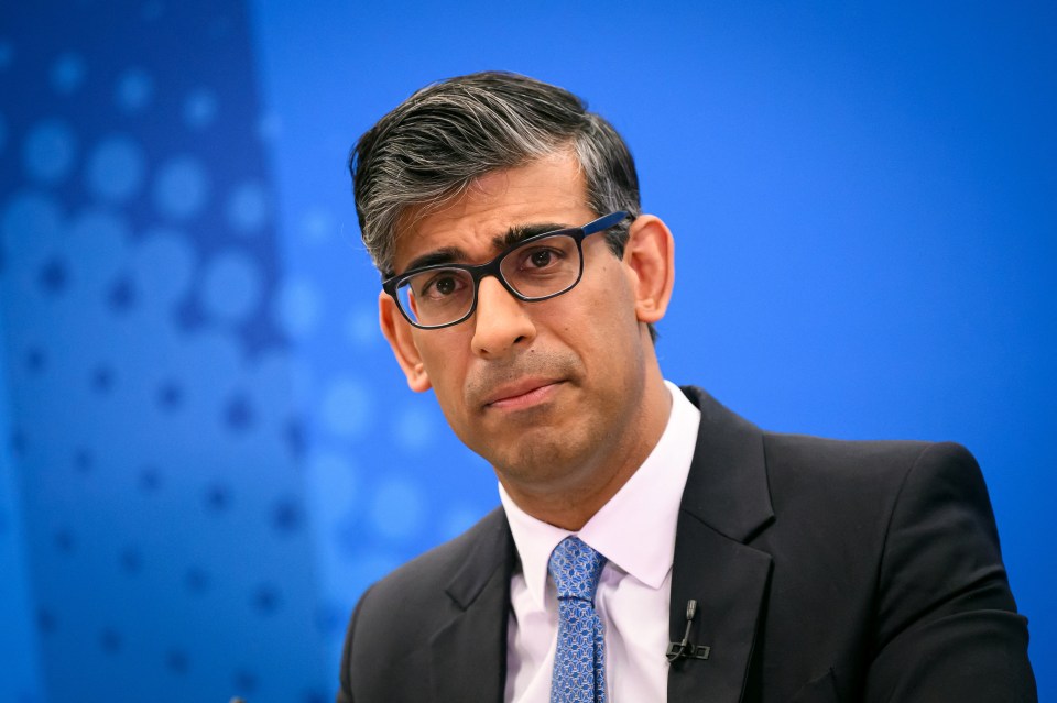a man wearing glasses and a suit looks at the camera