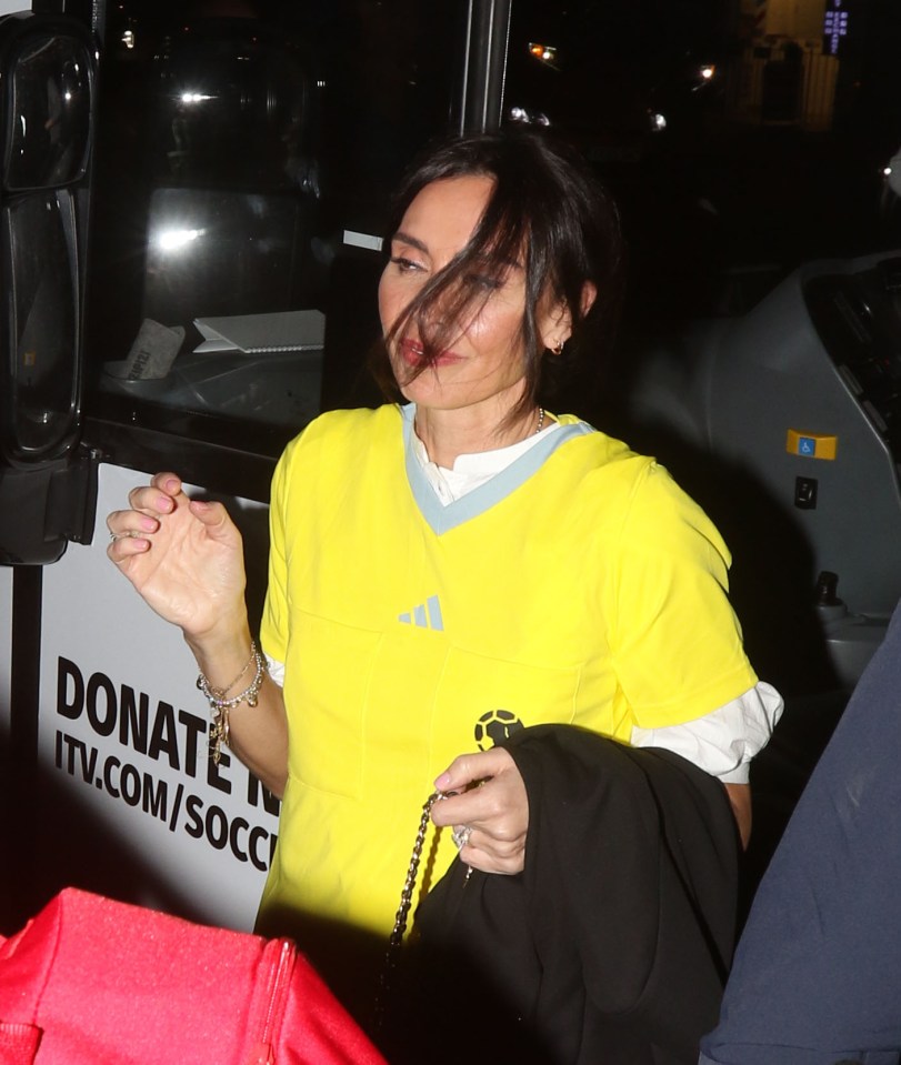 a woman wearing a yellow adidas shirt stands in front of a donate tv.com/soccer sign