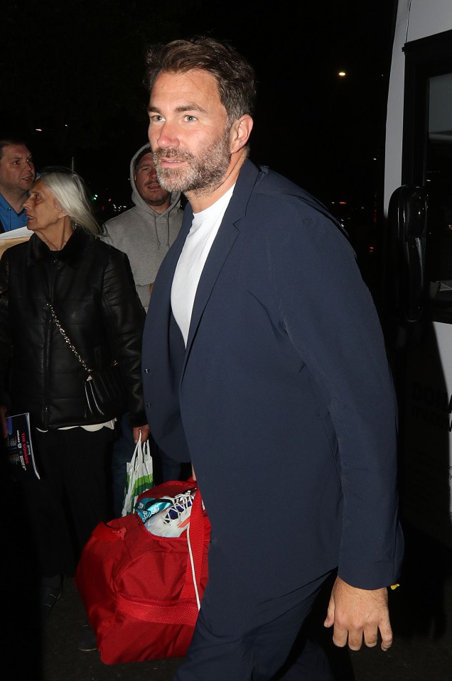 a man in a suit is carrying a red bag that says ' snickers ' on it