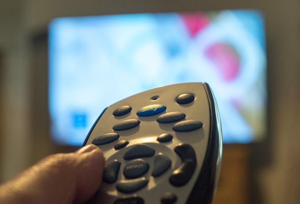 a person is holding a remote control in front of a tv