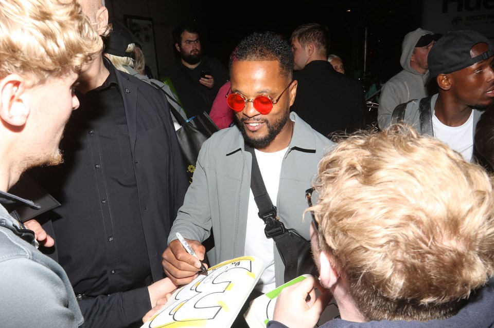 a man wearing red sunglasses signs a piece of paper