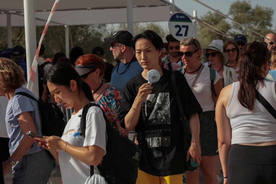 People have been seen with handheld fans as they walk around parts of Greece affected by the soaring heat