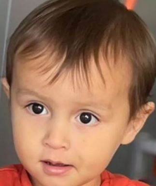 a close up of a baby 's face with a red shirt on .