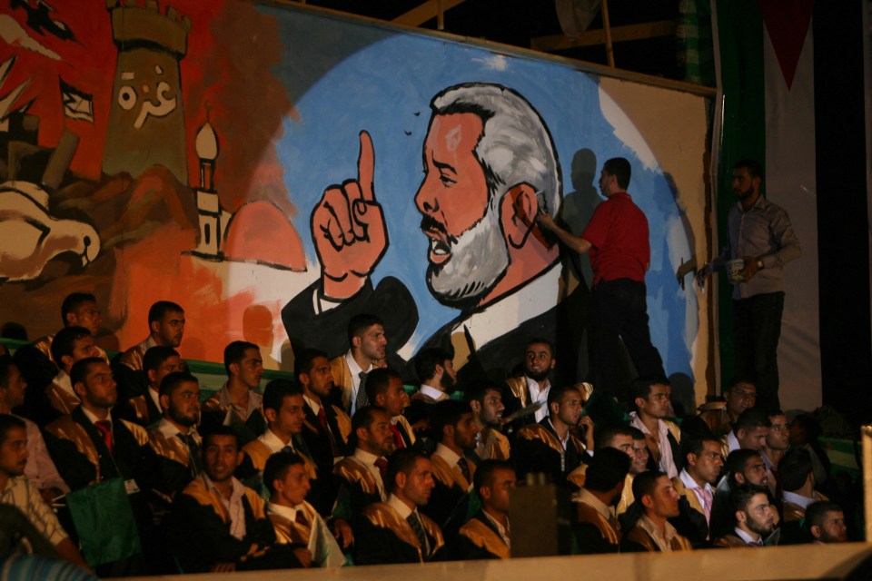 A man paints a wall with a picture of Haniyeh during a mass wedding ceremony in 2010