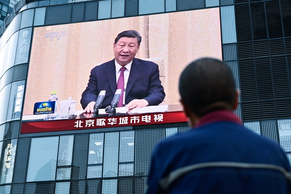a man sits in front of a large screen with chinese writing on it