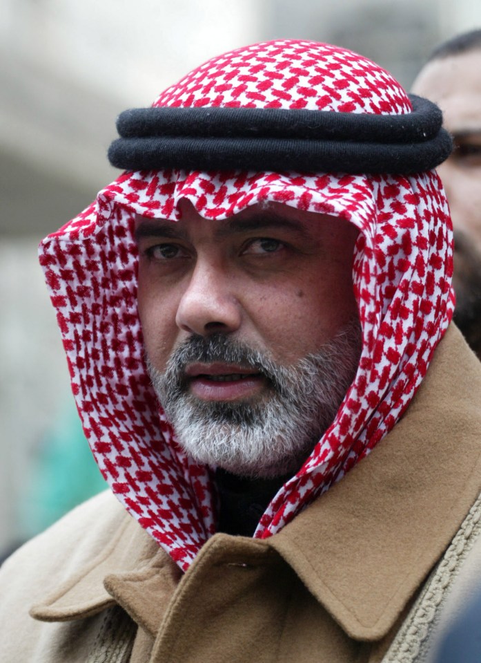 a man with a beard wears a red and white head scarf