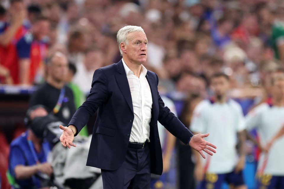 a man in a suit stands on a soccer field with his arms outstretched