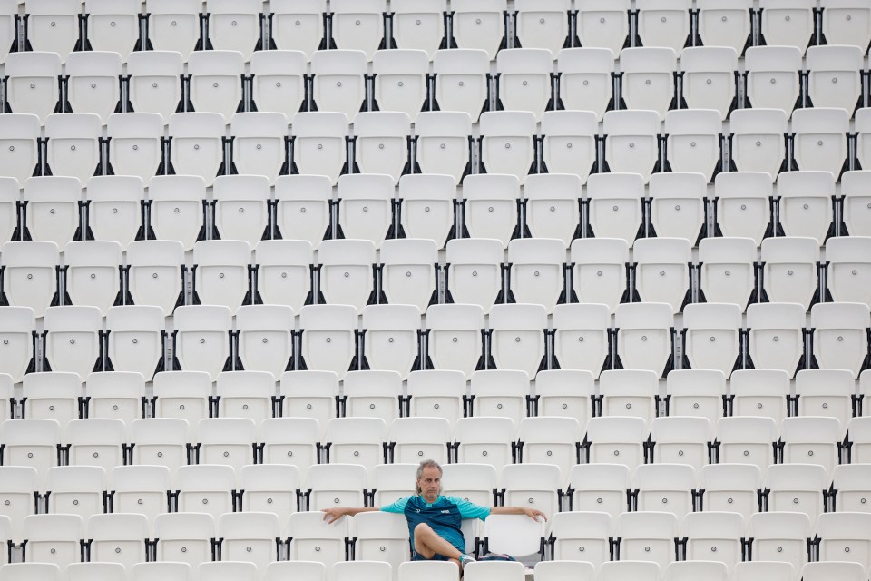 a man sits in a row of empty stadium seats