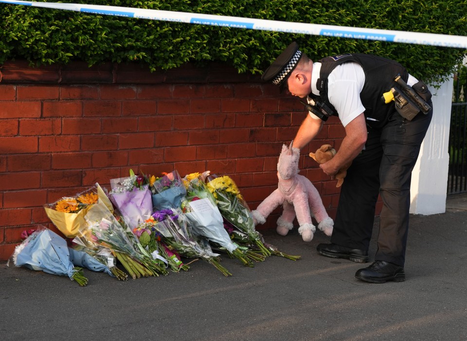 a police officer holds a stuffed animal in front of a bunch of flowers