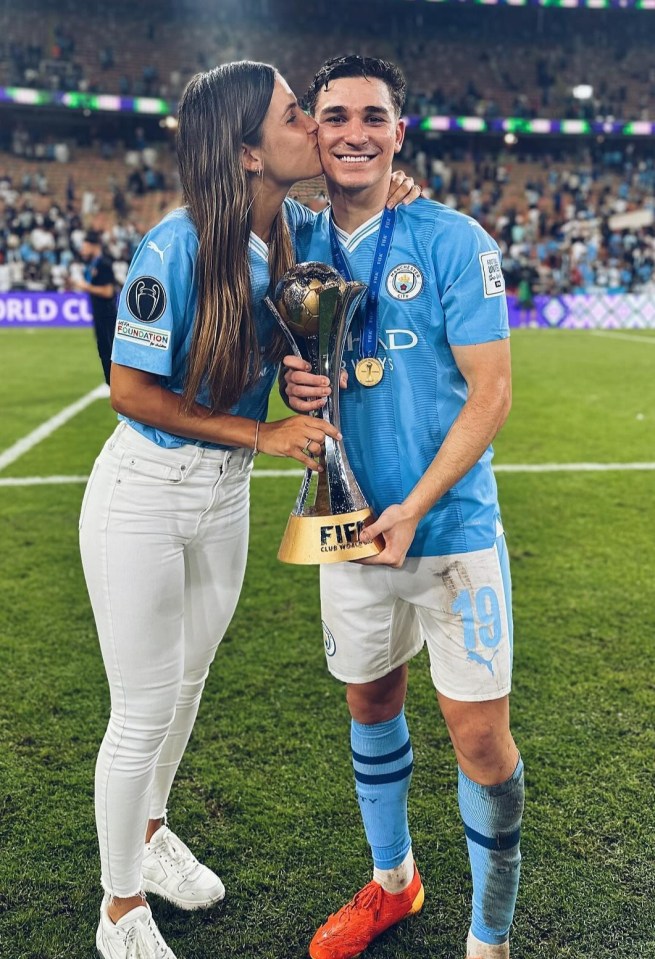 a woman kisses a soccer player who is holding a trophy