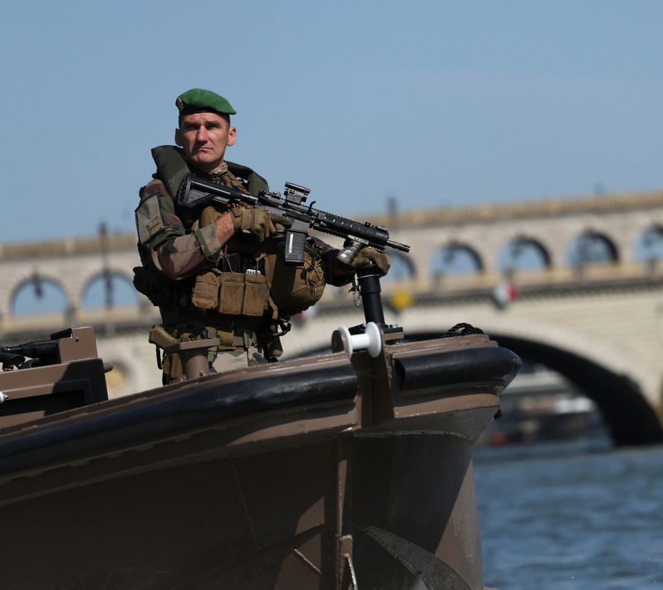 An armed soldier patrols the Seine River on a boat as officials look to place a secure barricade around the Games' venues