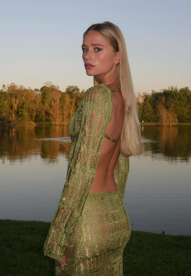 a woman in a green dress stands in front of a lake