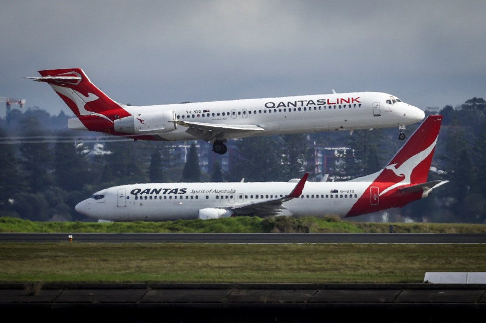 a qantas plane is flying over a smaller qantas plane
