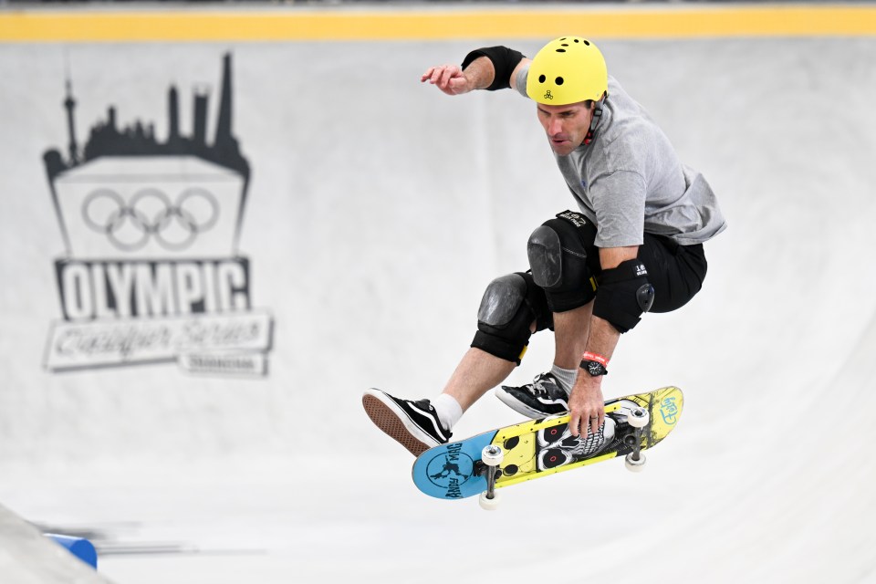 a skateboarder is doing a trick in front of a sign that says olympic