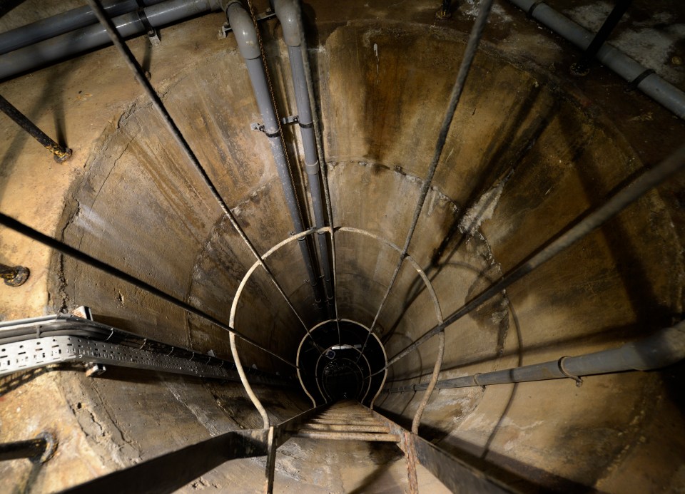 a spiral staircase going down a concrete tunnel