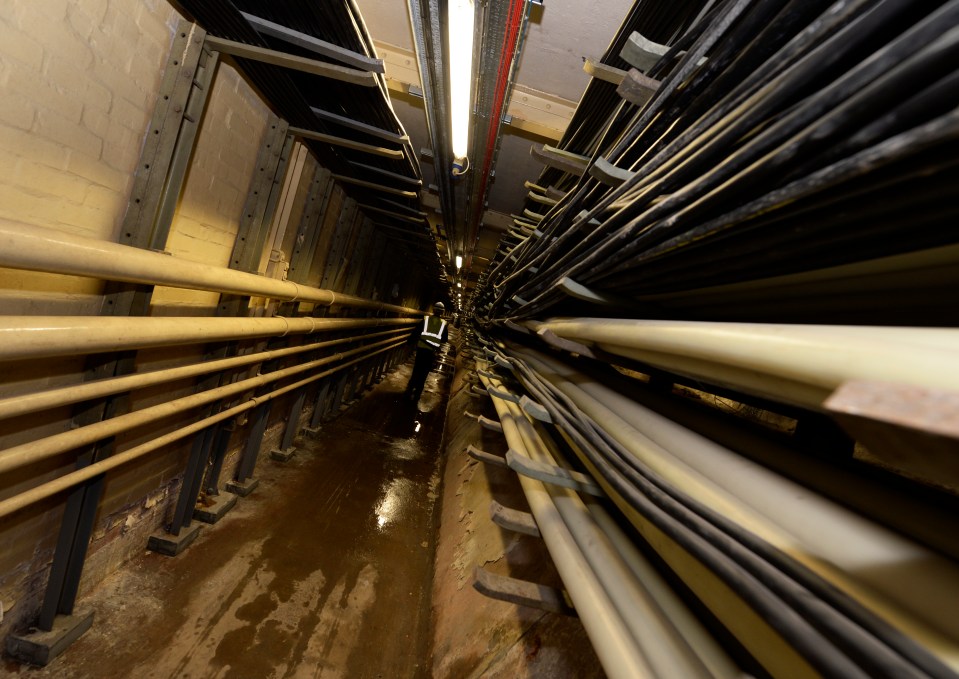 a narrow tunnel with a lot of wires and pipes