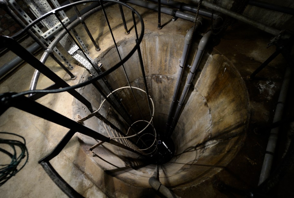 a spiral staircase in a dark room with a sign that says ' emergency exit ' on it