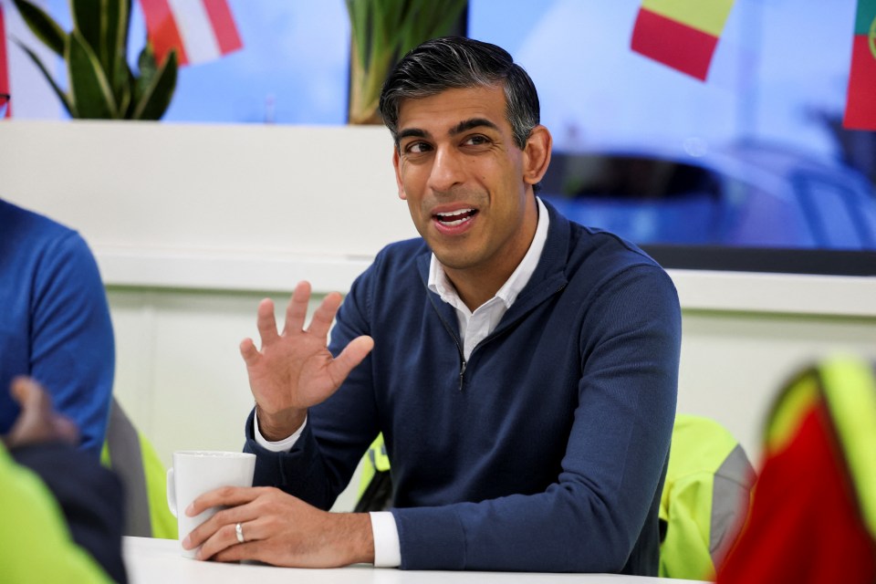 a man in a blue sweater sits at a table with a cup of coffee
