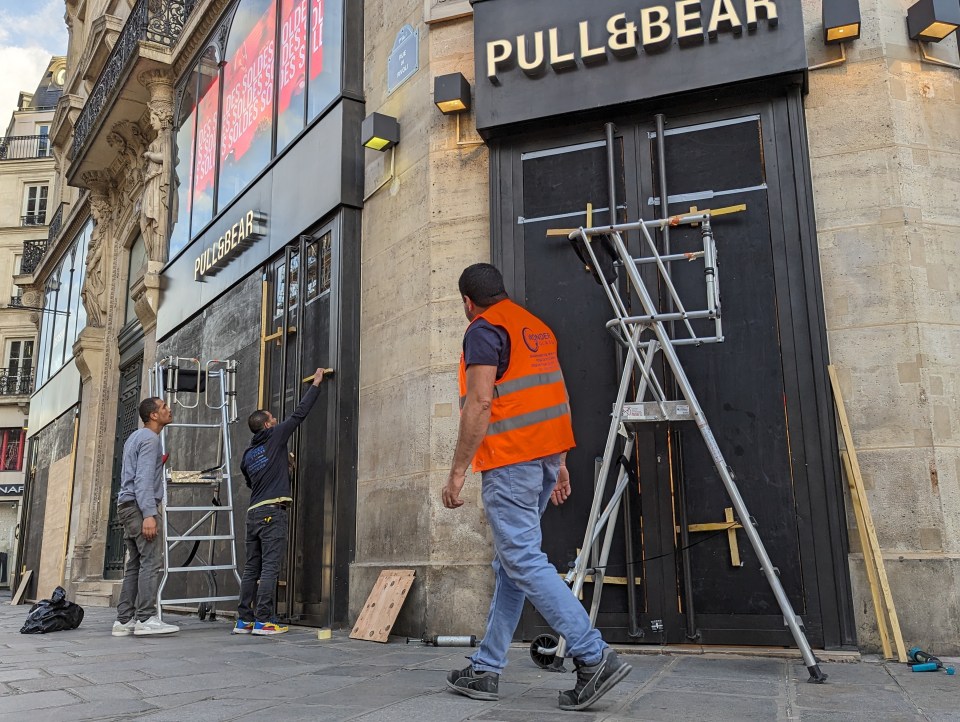 a man in an orange vest walks past a pull & bear store