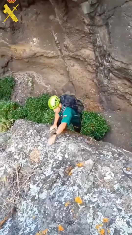 a man wearing a helmet is climbing up a rock wall