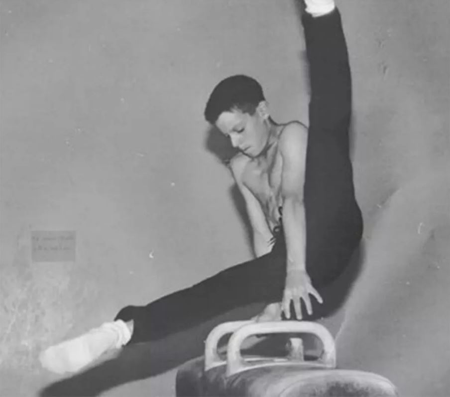 a young man is doing a split on a balance beam