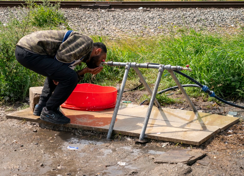 Migrant drinking and washing his face at a food bank