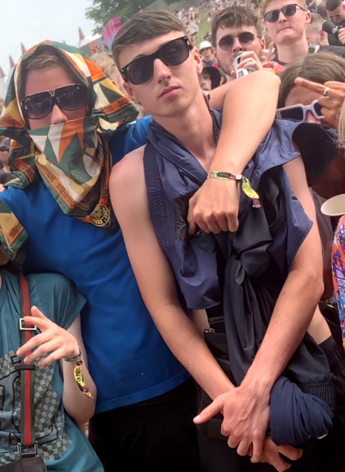 a man wearing sunglasses and a scarf around his head is being held by another man
