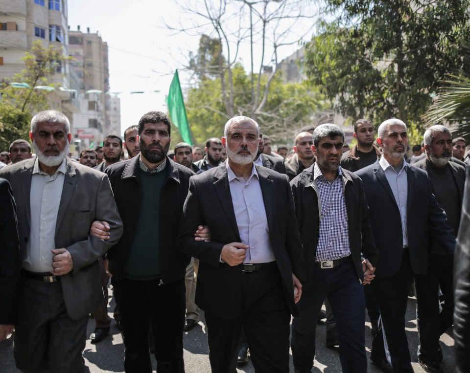 a group of men are walking down a street with a green flag in the background