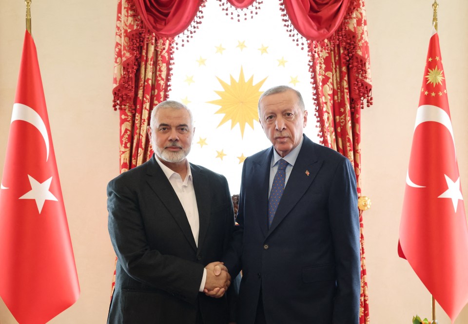 two men shaking hands in front of two flags