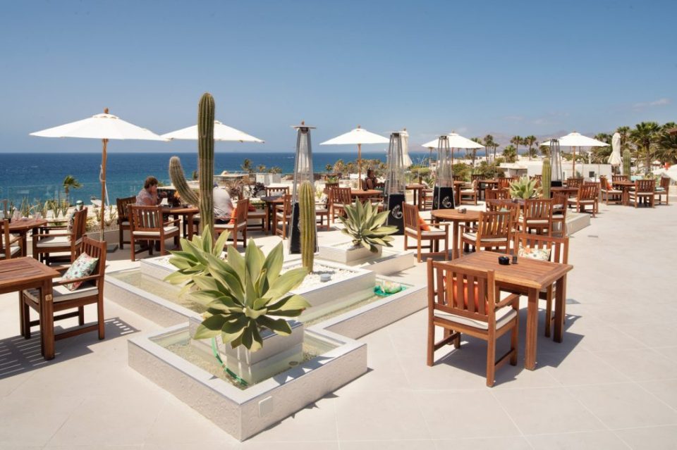 a restaurant with tables and chairs and umbrellas overlooking the ocean