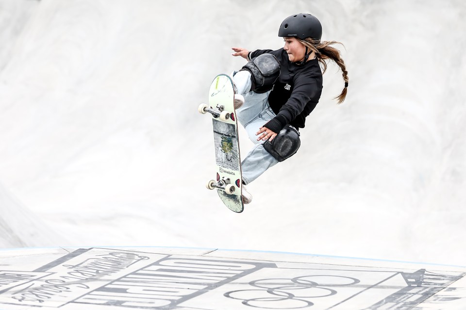a girl wearing a helmet is riding a skateboard in the air