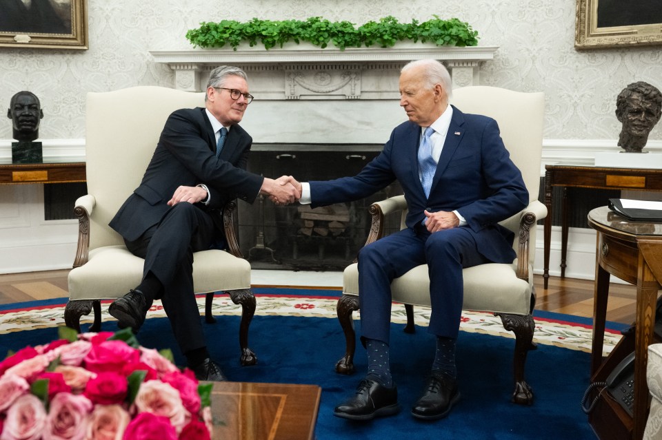two men shaking hands in front of a fireplace