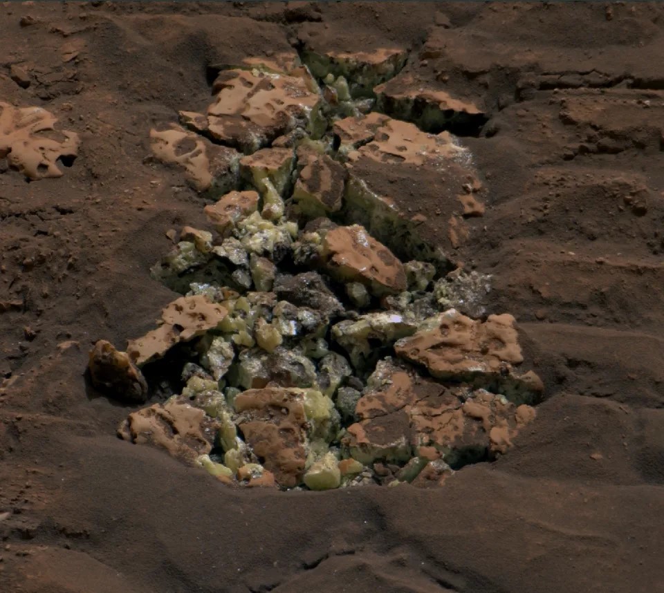 a pile of rocks in the dirt with a few green ones