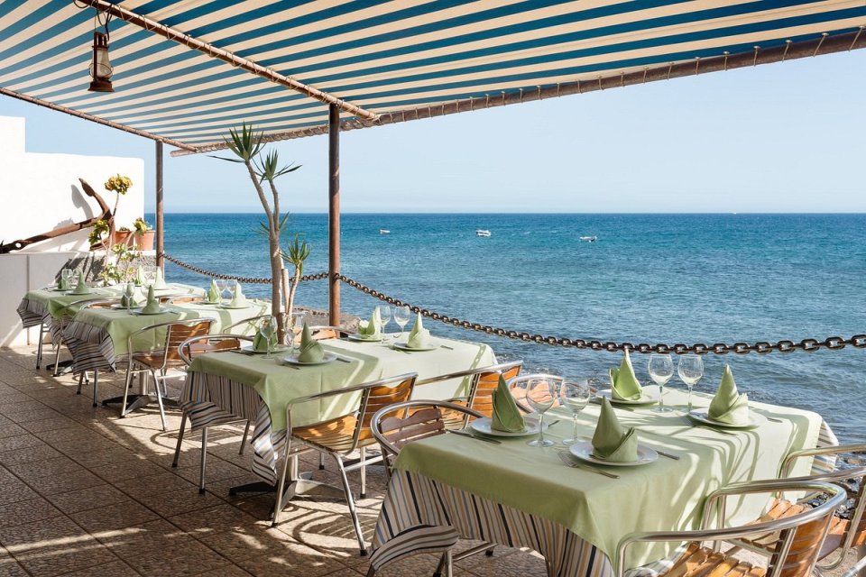 a restaurant with tables and chairs overlooking the ocean