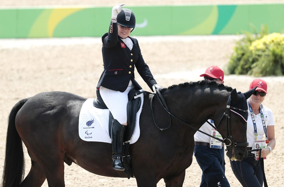 a woman riding a horse with the word paralympic on the saddle