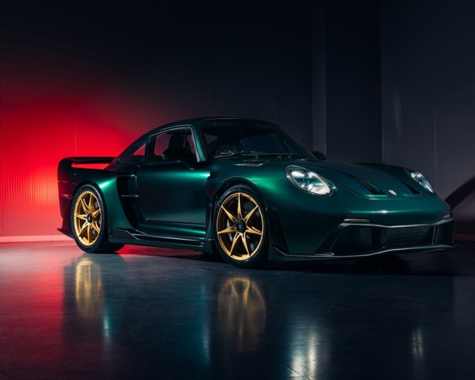 a green car with gold wheels is parked in a dark room
