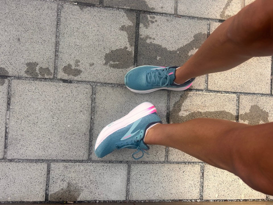 a person wearing a pair of blue and pink brooks shoes