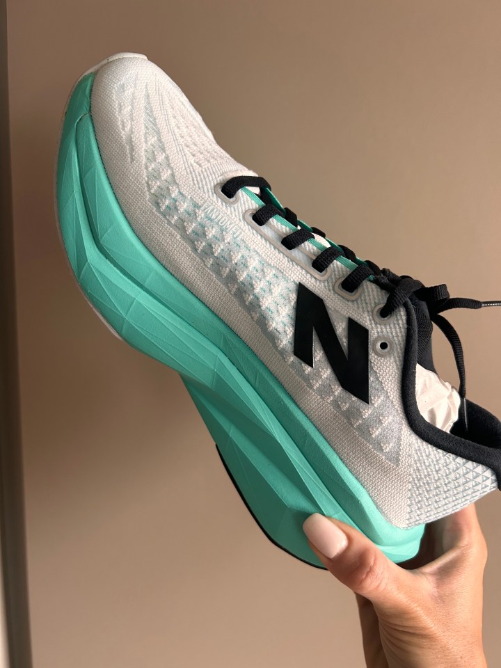 a person is holding a pair of new balance shoes