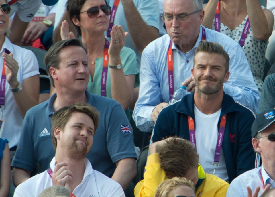 a man wearing an adidas shirt sits in a crowd